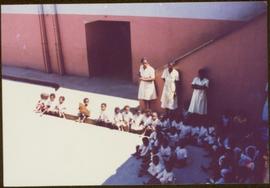 CUSO Mission in Angola - Three unidentified women stand over a group children seated in rows