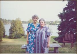 Iona Campagnolo and unidentified woman stand at stone bench overlooking a lake