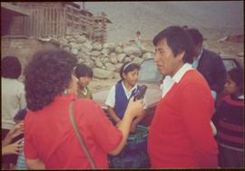 W.H.O. Trip, Ayacucho, Peru - Unidentified woman holding tape recorder to an unidentified man as children stand in background