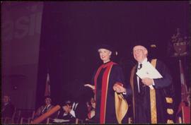 Honourary Doctor of Laws, Brock University - Iona Campagnolo grasping the hand of an unidentified man onstage, both in regalia