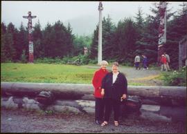 Iona Campagnolo and Margaret Anderson stand in front of totem poles