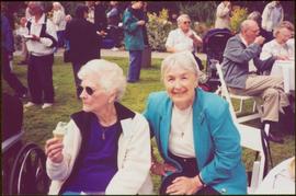 Two unidentified women sit together on crowded lawn at Government House in Victoria, BC