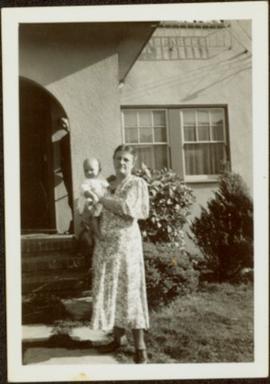 Woman Holding Infant in Front Yard
