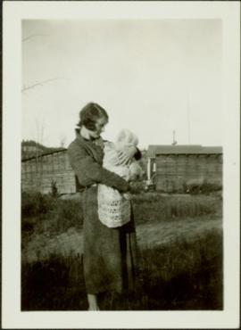 Woman Holding Infant in Farm Yard