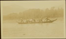 Close view of eight unidentified men poling a canoe up Nass River, BC