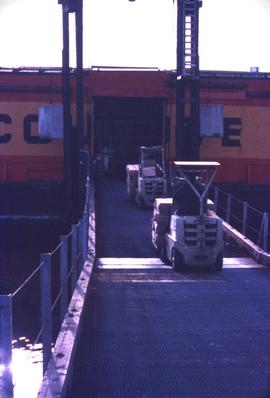 Forklifts taking asbestos pallets onto ship