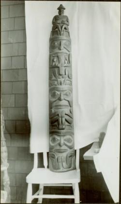 Model wooden totem pole on chair