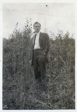 Man in jacket and tie posing in a field