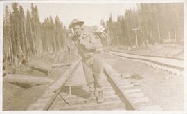 Man with walking stick on railroad tracks