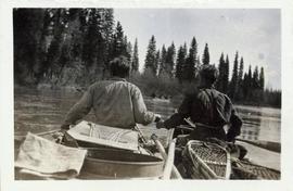 Two men sitting in canoes which are alongside one another