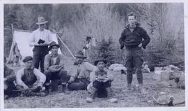 Several men seated on the ground in front of a tent