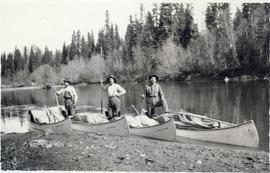 Three men standing in their canoes