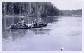 Three men paddling a canoe up a river