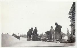 Several men loading a sled with gear