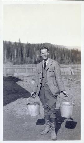 Man with two buckets going to feed the pigs