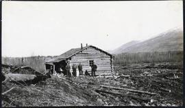Several men standing in front of a log building