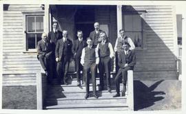 Several men standing on the front steps of a building