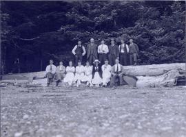 Several men and women sitting on logs on a beach