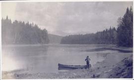 Man standing beside a canoe on the shore