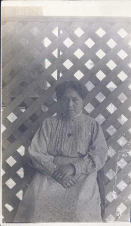 First Nations woman sitting in front of a lattice