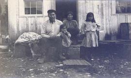 First Nations family sitting in front of a building