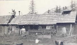 A man standing in front of a log house