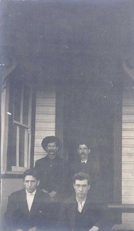 Four men sitting on the front steps of a building