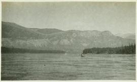 A canoe on a body of water with the mountains in the background