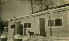 A man and a dog standing in front of the B.C. Police Barracks