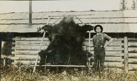 A man standing next to a stretched bear skin