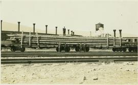 Grand Truck Pacific flatcars loaded with long logs and men posing in front