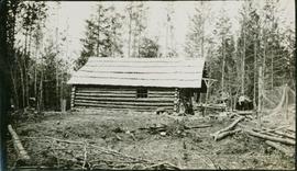 A man standing next to a log cabin