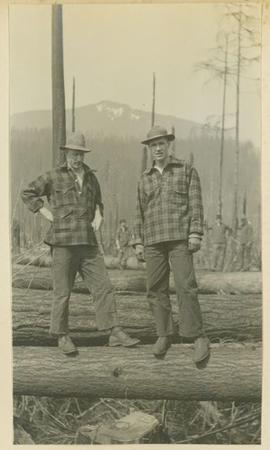 Two men standing on top of a log
