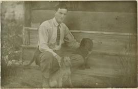 A man sitting on some stairs with two small dogs and a cat