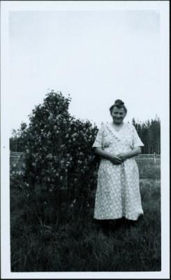 Mrs. John Marcoll Sr. standing in a field next to a lilac bush
