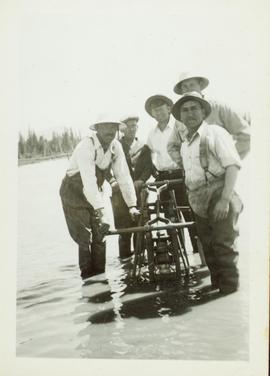 Five men standing in flood water beside a utility car on the CNR tracks