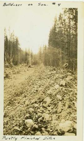 Ditch construction by bulldozer within a forested landscape
