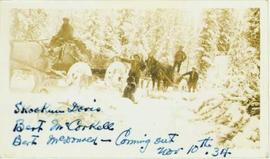 Four men posed within or beside two horse drawn carriages in a winter landscape