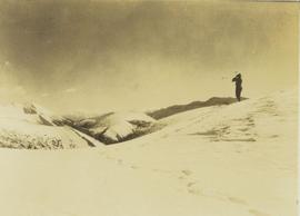 Lone man surveying the landscape from a snowy peak