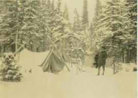 Two men standing at a snow-covered campsite