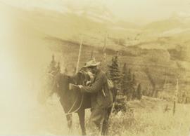 Prentiss Gray standing with his horse and rifle