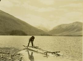 Johnny Napolean using an auger to build a makeshift raft on Muinok Lake