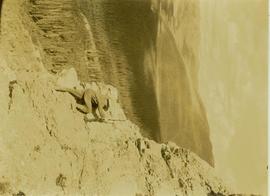 Prentiss Gray, rifle in hand, scaling a cliff in search of game