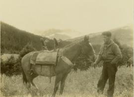 Pete Callao standing next to the pack horse wearing a saddle designed to carry Gray's camera equipment