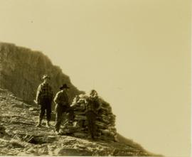 (L-R) Bob Potts, Joe (?) Callao and an unidentified man looking for game from a hilltop cairn