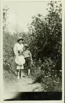 Woman standing on a dirt path with two young boys