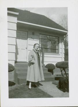 Woman (Florence Hawkes?) standing outside of a house