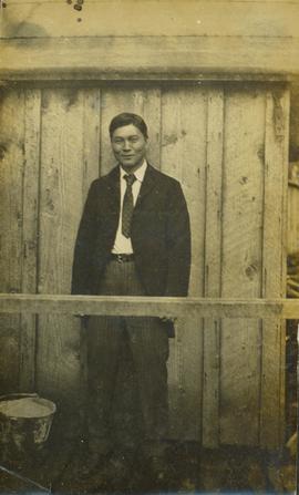 Man of Japanese descent wearing suit and tie and posing for a photograph