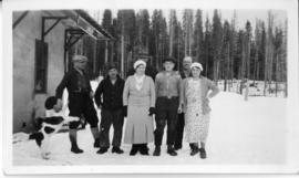 A group of 5 males, two females and a dog posing for a photograph at Lindup railroad station near
