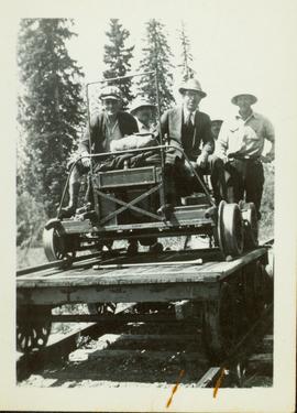 Small flatcar loaded with four men and a speeder